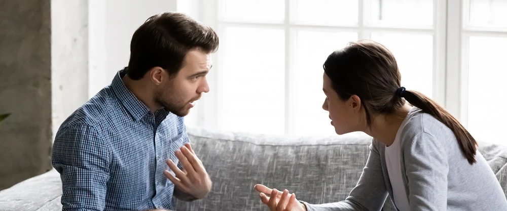A man and a woman arguing on a sofa