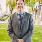Portrait of Mark Hodgson, family law attorney, in a gray suit and blue tie